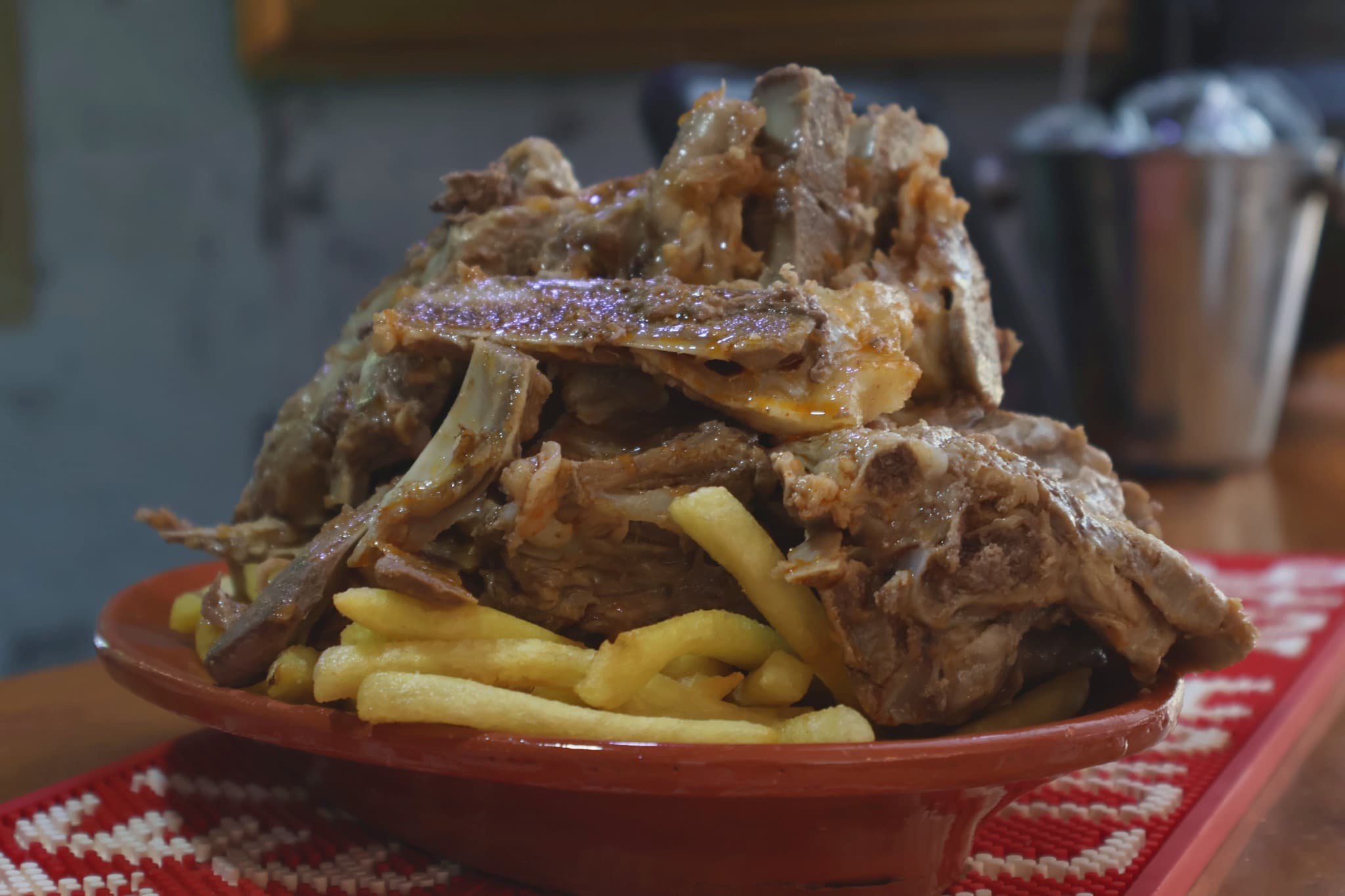 Ossos, o prato da casa, servidos com batata frita num prato de barro generoso.